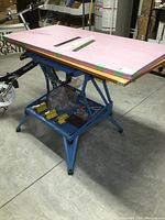 Full view of the blue Black & Decker Workmate 400 workbench with extra wood and styrofoam work tops stacked on it.