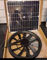 Box containing black 10-inch solar powered ventilation fan and solar panel with grid cells.