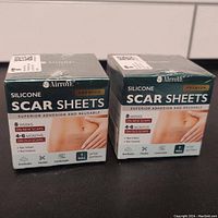 Two unopened boxes of Airroye Silicone Scar Sheets showing front packaging with usage details and dimensions.