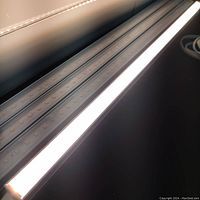 Closeup of two LED light bars illuminated, showing the light diffused through the translucent covers and the rows of LEDs inside.