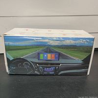 Box showing the device mounted on a car dashboard with a road view background, illustrating usage of the media player screen.