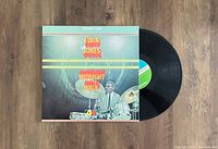 Photo showing the front of the vinyl record cover and the vinyl disc partially out of the sleeve.