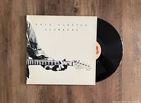 Photo showing the vinyl LP record partially out of its cover, cover shows black and white image of Eric Clapton playing guitar, with title 'Eric Clapton Slowhand'.