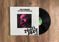 Photo of the vinyl record partially pulled out of the album cover showing the front cover design and record label.