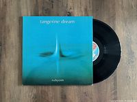 Tangerine Dream Rubycon LP vinyl record partially out of its album cover showing the front cover art and the black vinyl disc with center label.