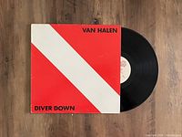 Front cover of Van Halen Diver Down LP showing red and white diagonal striped cover and partially pulled vinyl record.