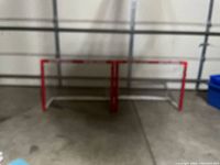 Both Bauer mini nets visible side-by-side on the floor behind a wire rack, showing red frame and white netting.