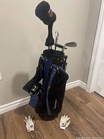 Photo showing the Tourmission golf bag with clubs inside and two white golf gloves on the floor in front of the bag.