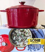 Photo of red Lodge enameled cast iron Dutch oven resting on box showing front profile and stainless steel knob.