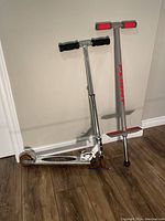 Photo showing Flight pogo stick next to Motion Board scooter, highlighting red and silver colors on pogo stick and chrome scooter frame.