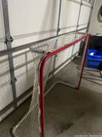 Side angle view showing red steel frame and white mesh netting.