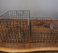 Two stackable wire storage baskets side by side on a wooden surface showing dimensions and build.