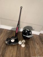 Full lot displayed with helmet, glove, bat, and four balls on wood floor against white wall
