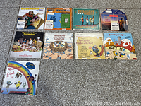 Ten vintage children's vinyl record albums laid out on a gray surface.
