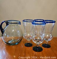 Photo showing the Mexican recycled glass pitcher and four matching glasses on a wooden surface.