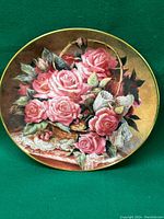 Full view of the round decorative plate depicting pink roses in a basket, lace accents and a gold rim.