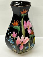 Front view of the hand painted floral vase on black background showing pink, orange, blue, and green floral motifs with gold rim on top.