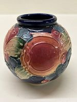 Front view of the vintage ceramic vase showing embossed fruit and leaf patterns with glossy glaze