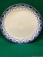 Full view of the antique plate showing blue ornate floral and leaf patterned border with gold rim and plain white center.
