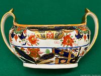 Front and side view of the antique Spode Imari sugar bowl showing floral and geometric patterns in vibrant orange, blue, green, and gold.