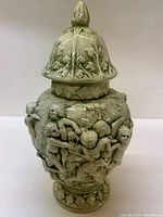 Front side of the Victorian urn showing cherubs in high relief and the decorative lid.