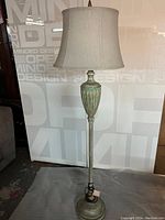 Full view of the vintage style floor lamp standing 60 inches tall with beige fabric shade and weathered green and bronze metal base.