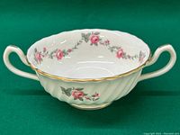 Front detail showing white ceramic soup cup with pink rose floral pattern and gold scalloped rim.