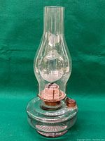 Full view of the vintage oil lantern showing the glass body and tall chimney.