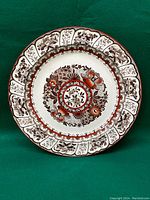 Full view of the Wedgwood Pekin plate showing the detailed floral pattern and scalloped edges in brown and reddish orange.