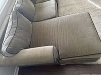 Close-up of the chaise lounge part of the sectional sofa showing gray upholstery with dark piping and plush cushion.