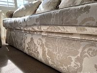 Close-up of the sofa base fabric showing damask pattern and construction detail