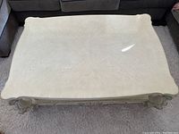 Top view of cream-colored wood coffee table showing textured surface and curved edges.