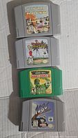 Four Nintendo 64 game cartridges laid out, showing labels for Star Wars Episode I Racer, Weather Country Club, Army Men Sarge's Heroes 2, and 1080 Snowboarding.