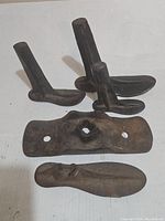 Photo showing all four cast iron shoe forms laid out on white background, displaying varied shapes and signs of wear.