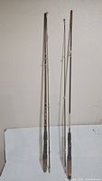 Full view of both fishing rods standing upright against a wall, showing overall size and condition.