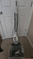 Full view of the Shark Professional SuperHeated Steam Mop standing upright against a door on carpet.