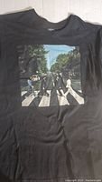 Front of the black T-shirt showing the Abbey Road crossing image with the four Beatles crossing the street.