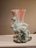 Front view of the pottery vase showing two deer figures and pink flared top with naturalistic base.