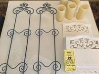 Photo of blue metal plate holders, white carved wooden decor pieces, and four battery candles on a white tablecloth