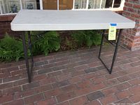 Front view of the folding table on brick floor with plants in background.