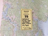 Lot with a large geological survey map spread out on the table and a label showing the lot specifics of 22 maps of Maine quadrangle areas for display or collection.