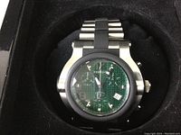Front view of Renato wristwatch showing green carbon fiber dial, chronograph subdials, and stainless steel band with black rubber accents.