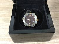 Front angled photo of Renato quartz watch in black velvet-lined case showing stainless steel case with gold screws and brown dial with chronograph subdials