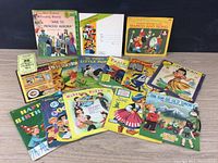 Photo showing a variety of vintage children's record envelopes and sleeves arranged on a black surface. Includes multiple titles with colorful graphics and illustrations.
