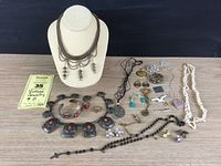 Full lot showing all jewelry items on table including necklace on display bust, bracelets, earrings, pins, and other pieces.