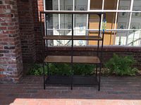 Front view of Ikea shelving unit with wooden shelves and black metal frame, showing overall condition and shelving layout.