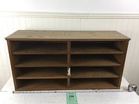 Front view of the wooden organizer showing eight compartments with sliding shelves, measuring tape in front for size reference.