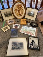 Overview photo showing all framed artworks, vintage prints, tiles, and the pressed flowers arrangement on carpeted floor.