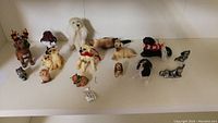 Full view of 13 assorted animal figurines including various dogs and other small animals on a white surface