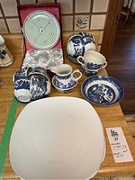 Blue and white cups, saucers, cream and sugar set, boxed doll size green and white china, three large white plates on table